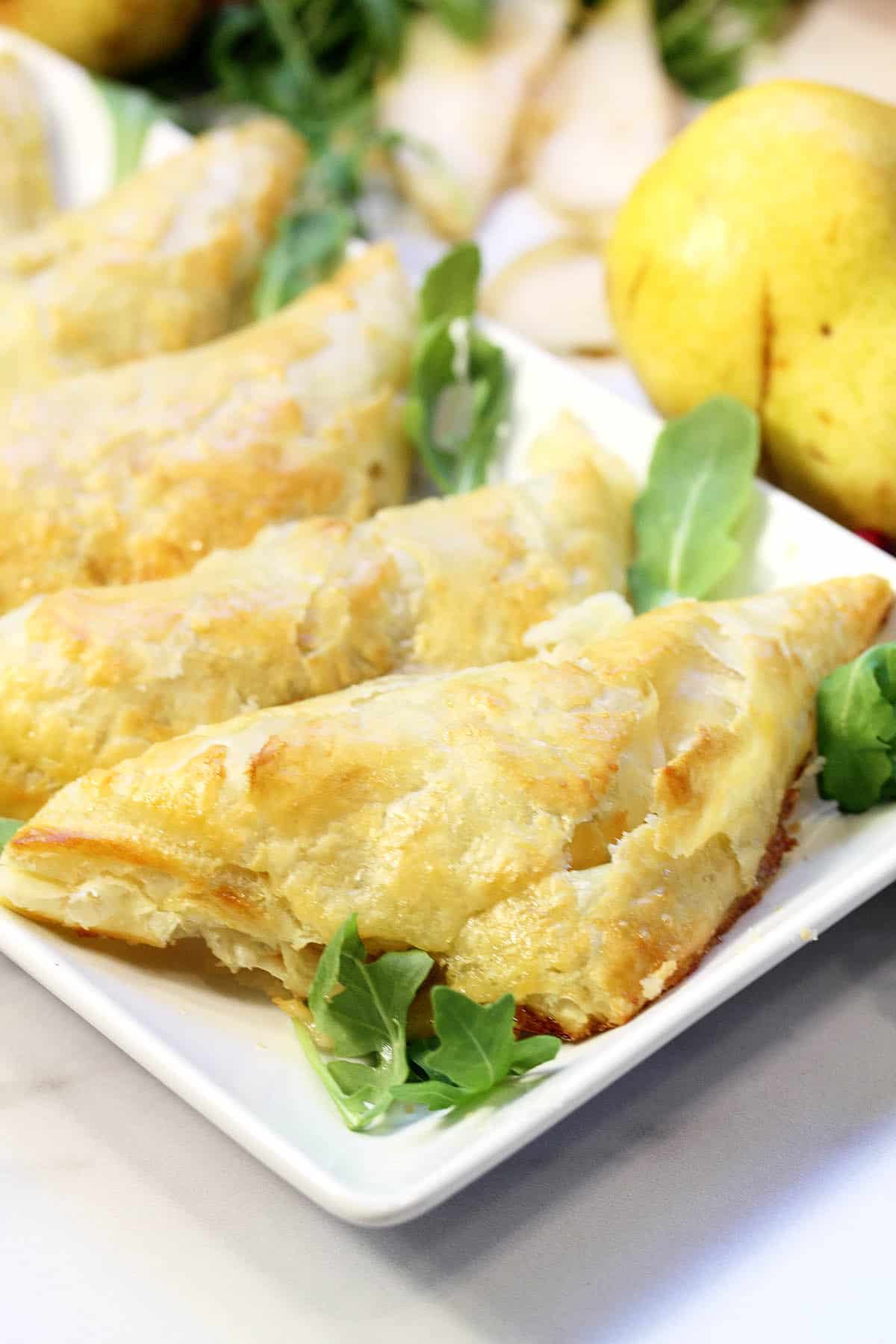 Closeup of puff pastry pocket on white platter with arugula.