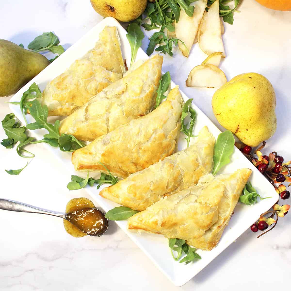 Overhead of ham and cheese pockets on platter with spoon of fig jam on side.