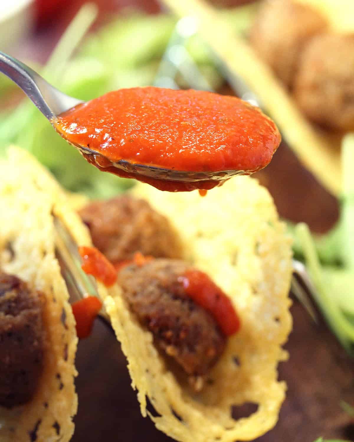 Closeup spoonful of Prego sauce over meatball tacos.