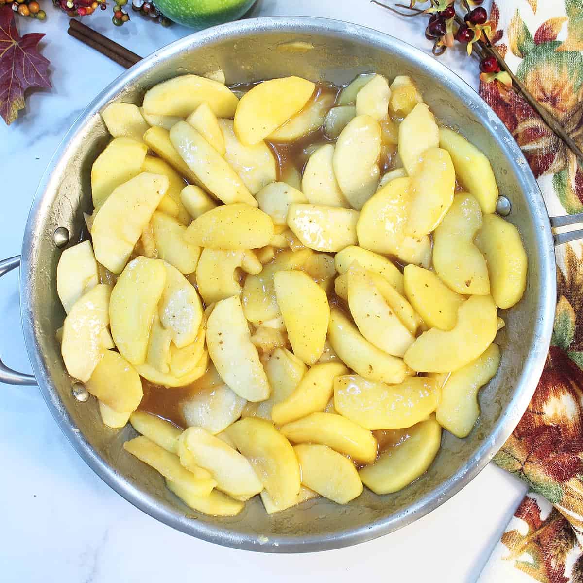 Cooked apples in skillet showing syrup base.