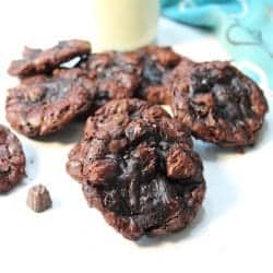 Cookies scattered around milk bottle on white table.