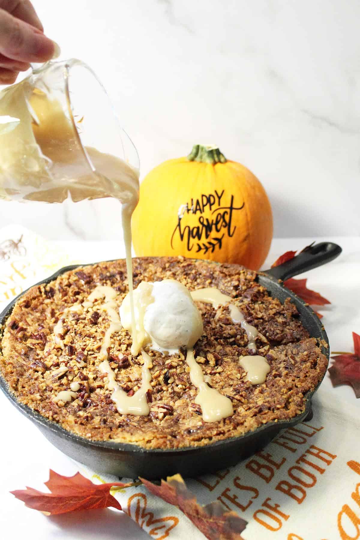 Pouring maple glaze on dump cake in skillet.