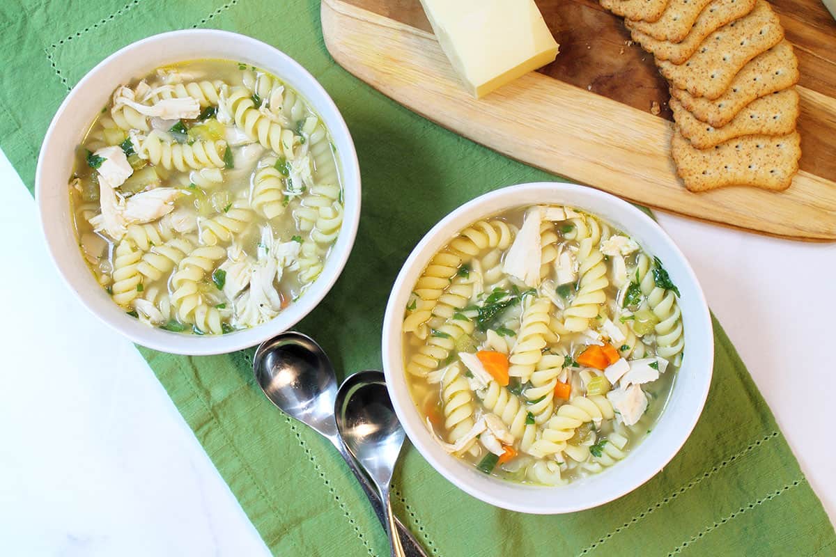 2 bowls of soup on green napkin with cheese tray.