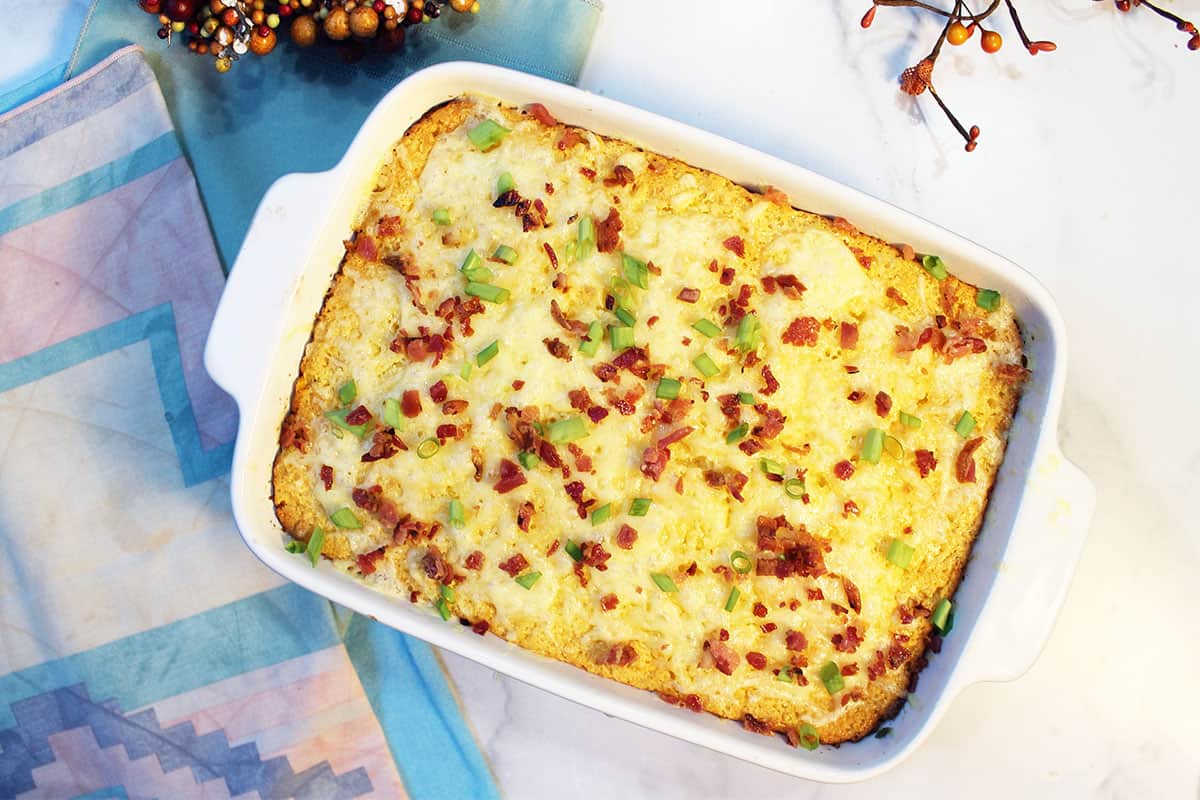 Baked casserole with bacon and green onion garnish.