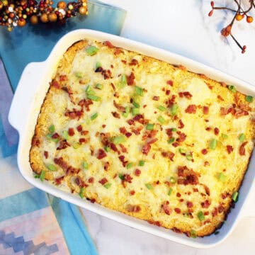 Baked cheesy Corn Pudding with bacon and green onion garnish.