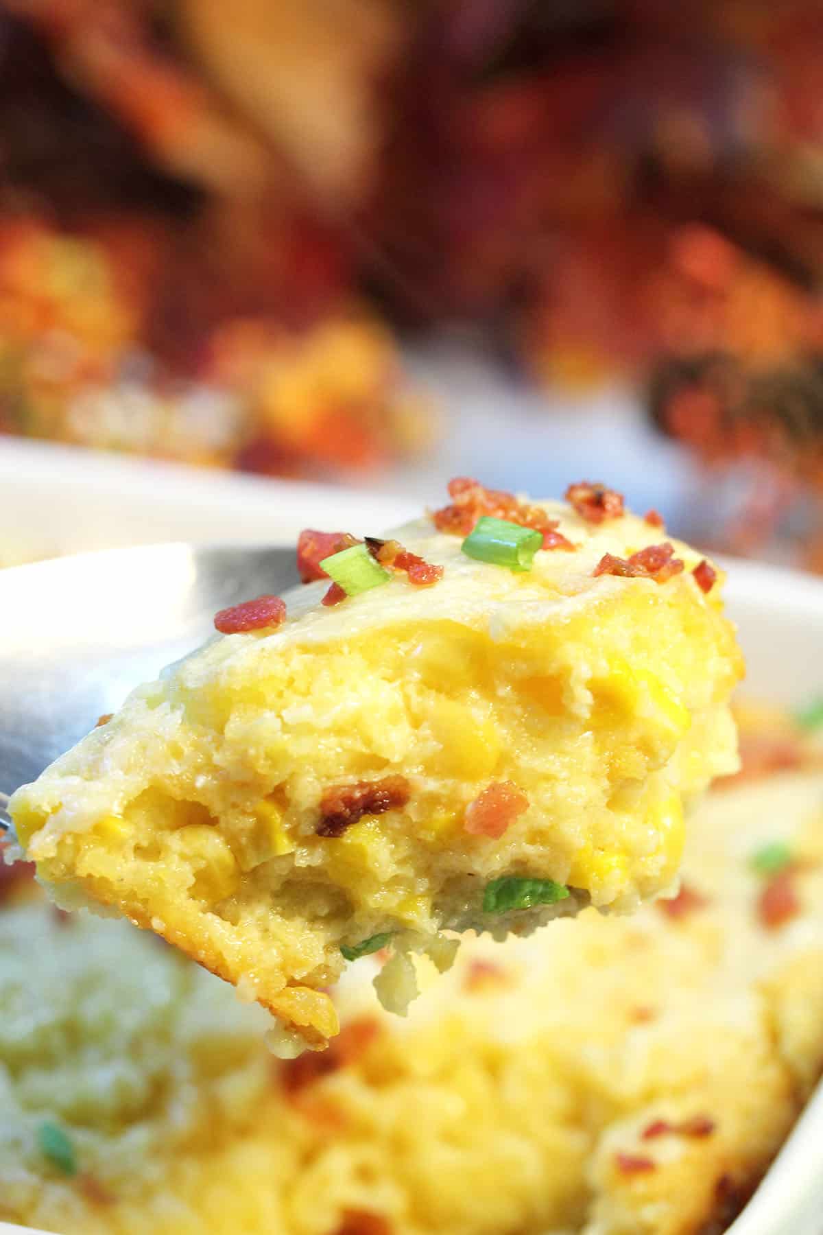 Spoonful of creamy corn pudding over casserole.