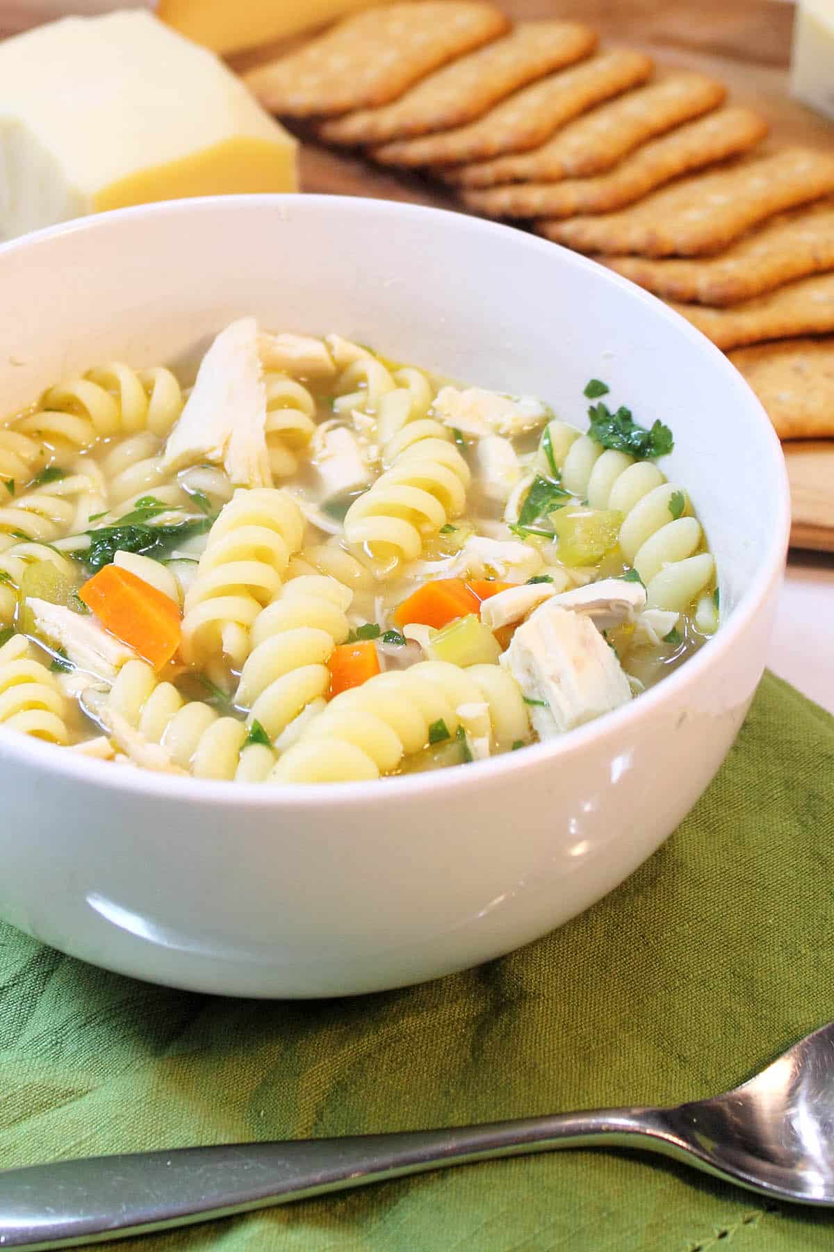 Full bowl of soup in front of crackers on cheese tray 