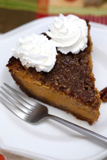 Slice of Pumpkin Pecan Pie on plate with whipped topping.