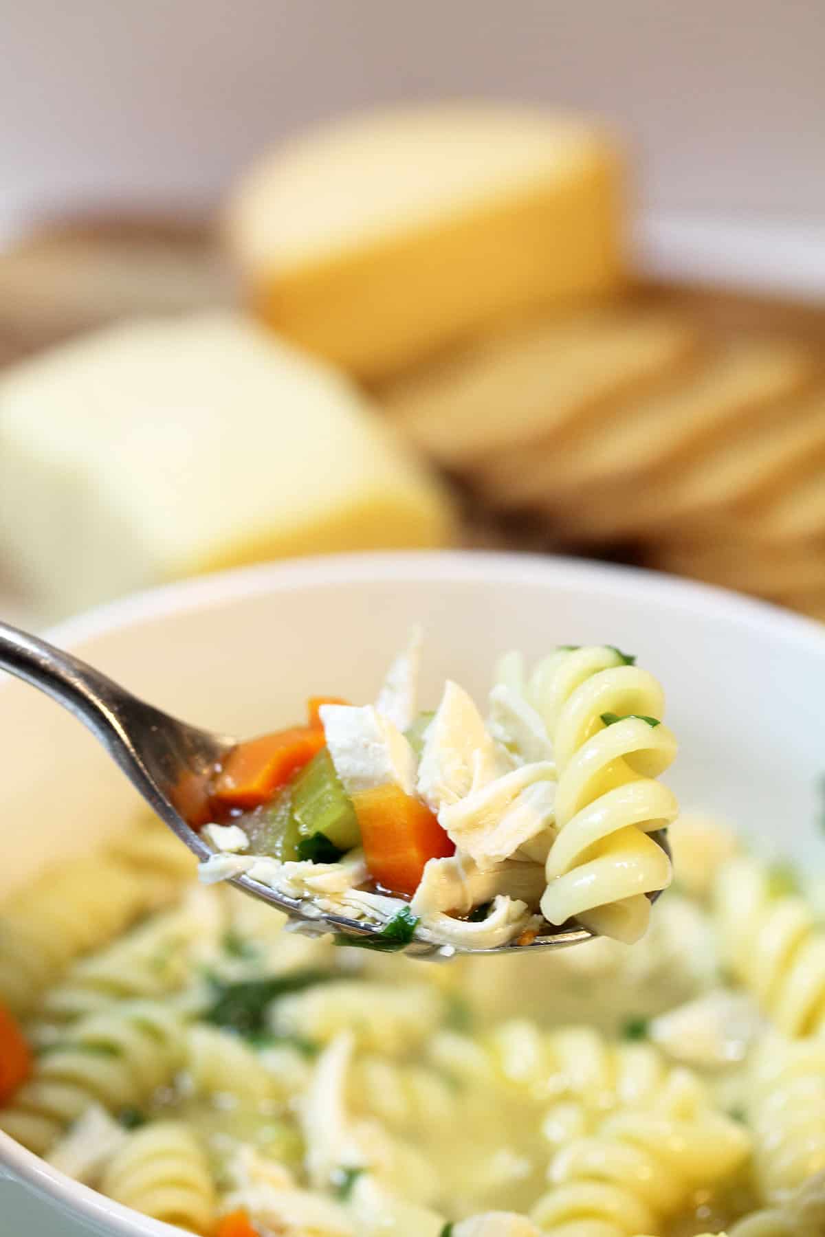 Spoonful of soup with cheese in background.