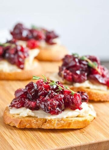 Cranberry Brie Crostini Appetizer on wooden board.