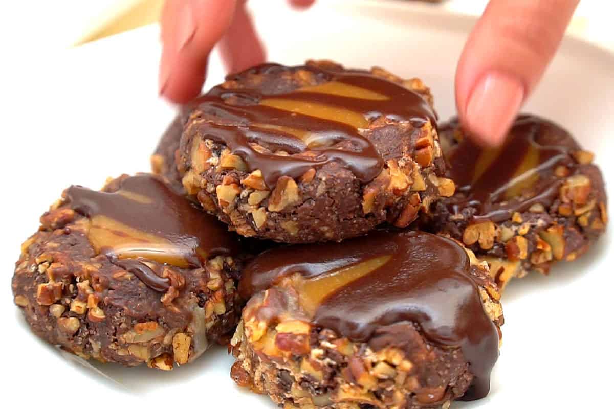 Reaching for turtle cookie on white plate.