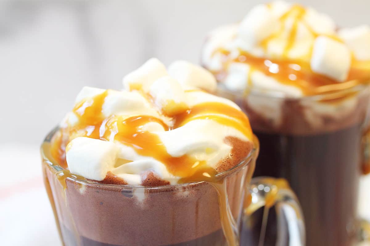 Closeup of whipped cream topped melted ice cream hot chocolate in mug.