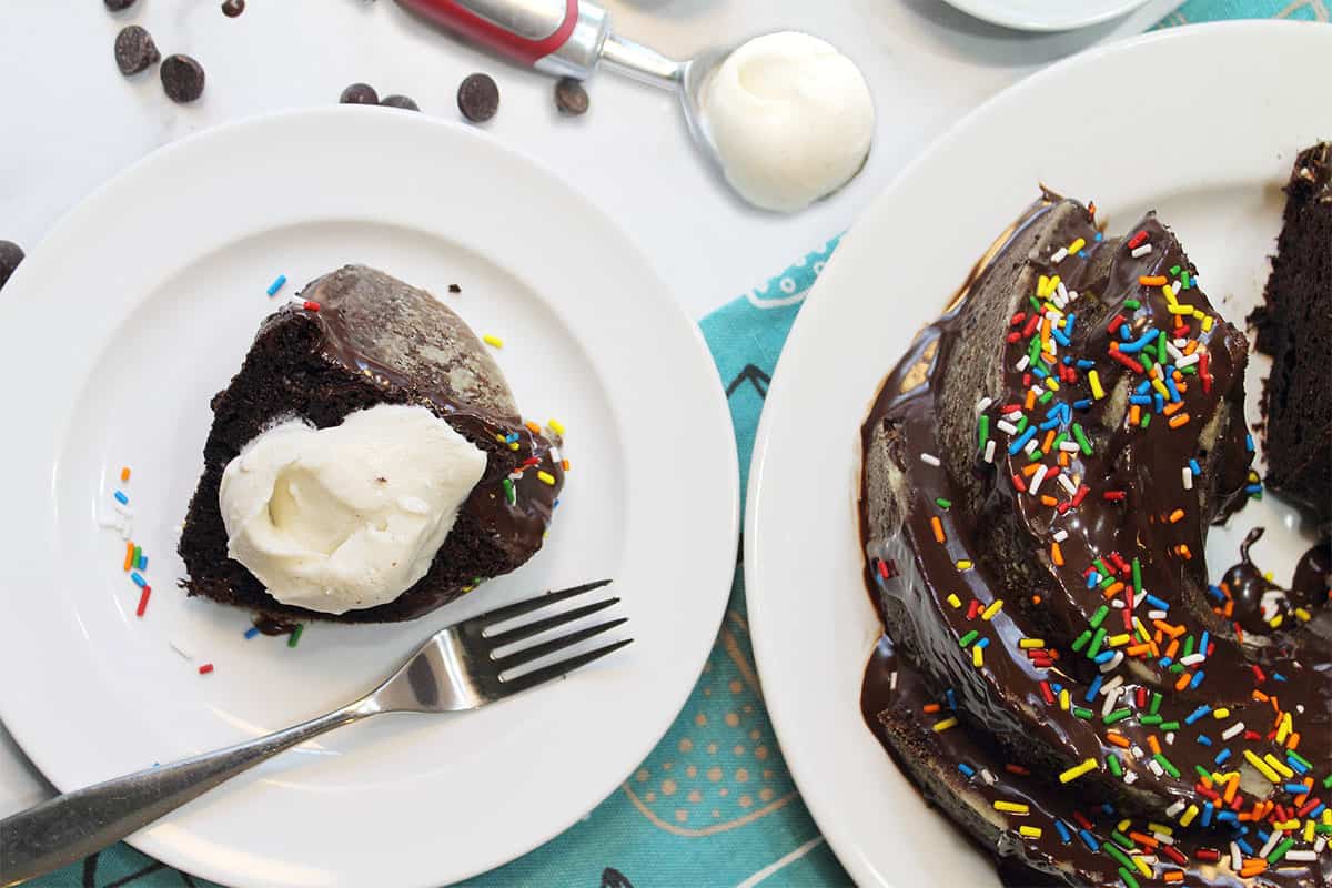 Slice of cake with ice cream next to full cake.