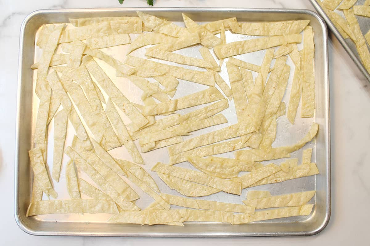 Tortilla strips coated with oil cut and spread out on cookie sheet.