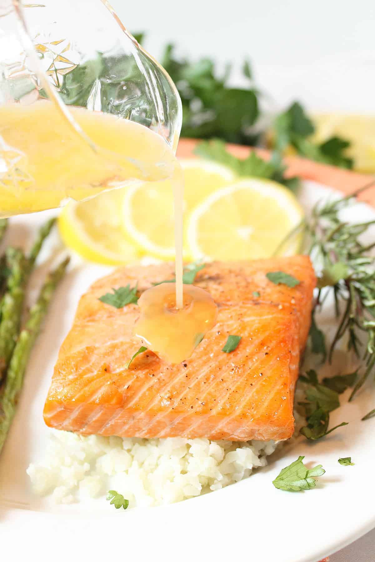 Drizzling butter sauce over air fried salmon.