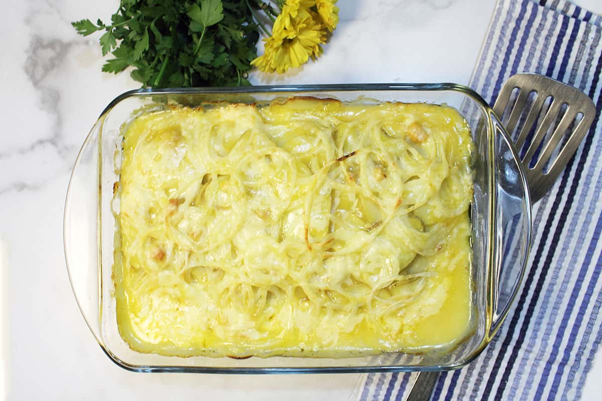 Baked casserole with spatula and blue striped towel next to it.