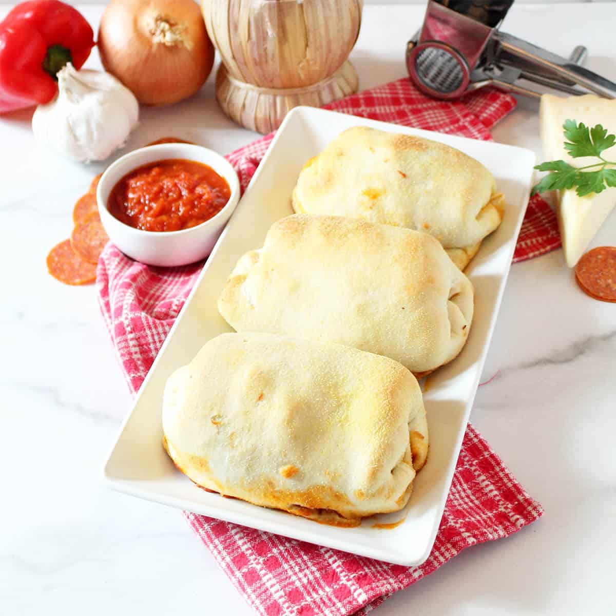 Baked stromboli on white platter with marinara dipping sauce.