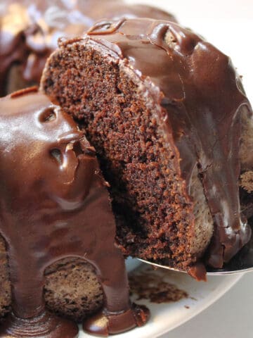 Lifting slice of cake from ganache covered chocolate pound cake.