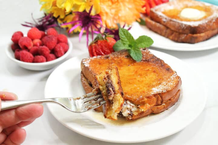 Bite on fork over plate with flowers  in back.