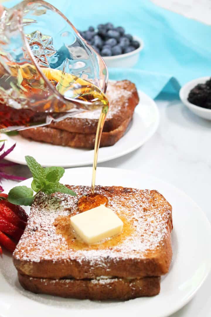 Pouring syrup over plated Cannoli Stuffed French Toast.