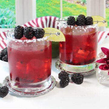 Two blackberry margaritas with garnish of berries and lime.