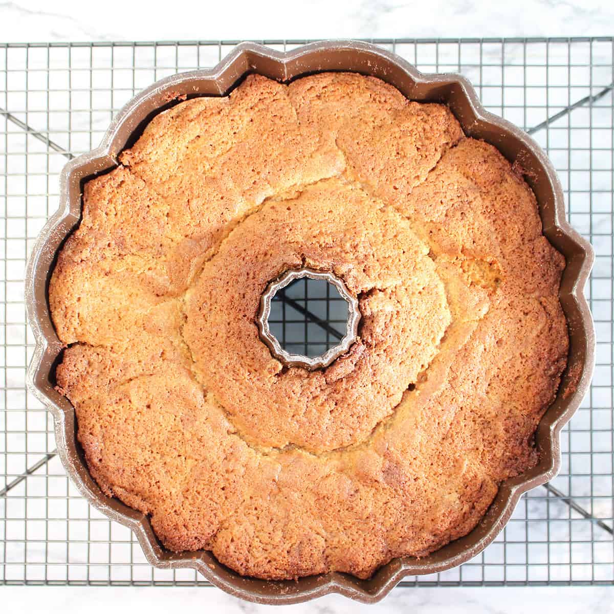 Baked milky way cake in bundt pan cooling on wire rack.