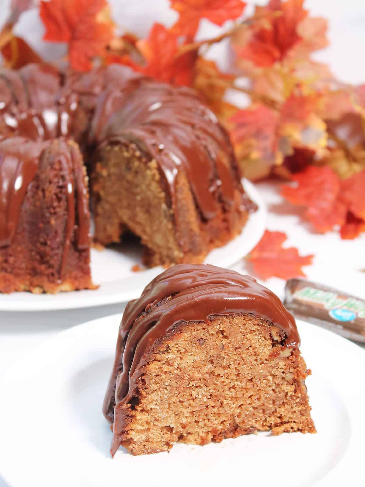 Slice of milky way cake on white plate in front of cut cake.