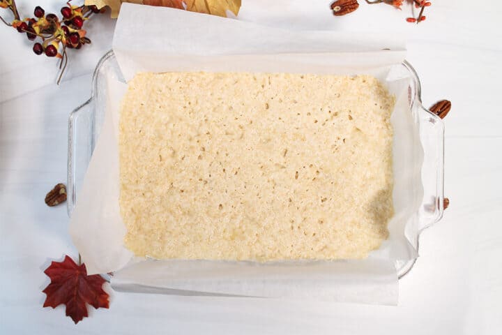 Baked shortbread crust in glass baking dish on white table.