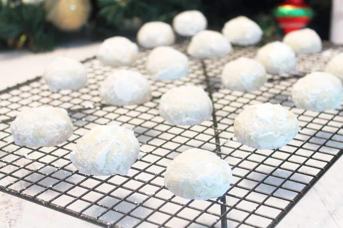 Powdered sugar coated snowball cookies on wire rack.