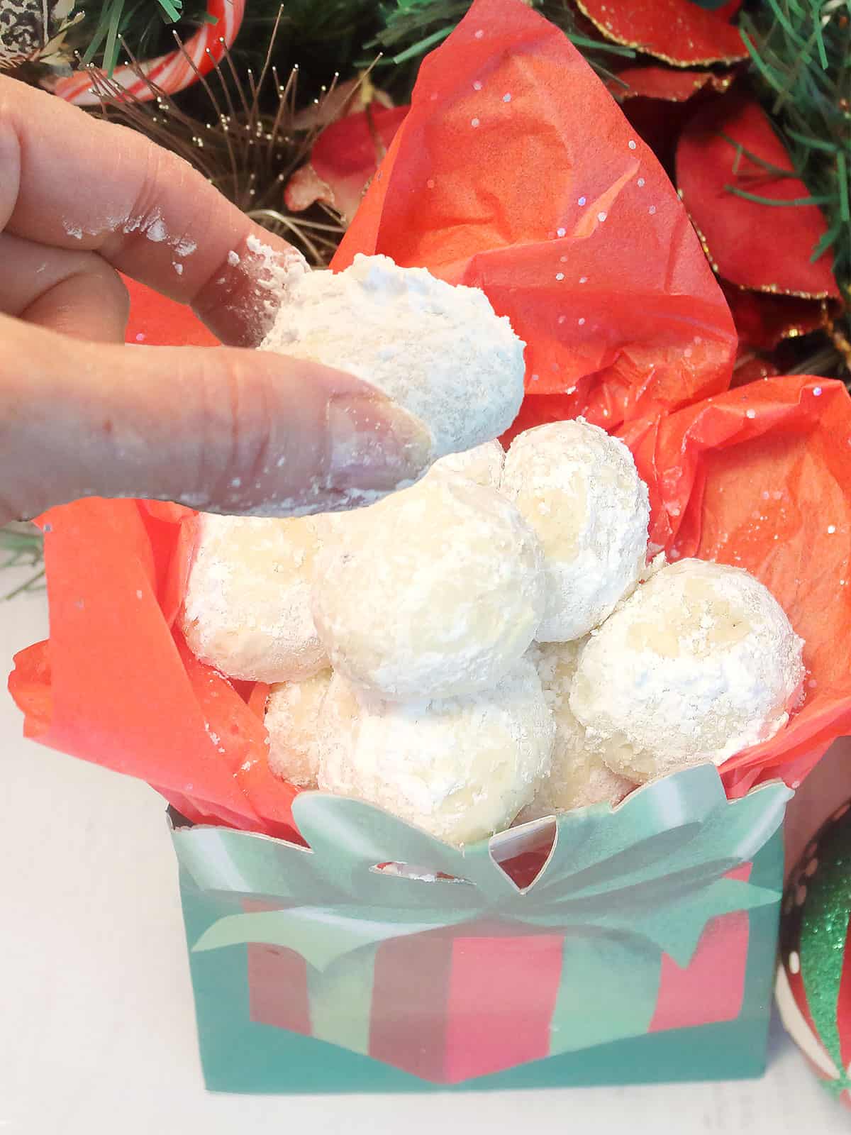 Lifting snowball cookie out of Christmas gift box.