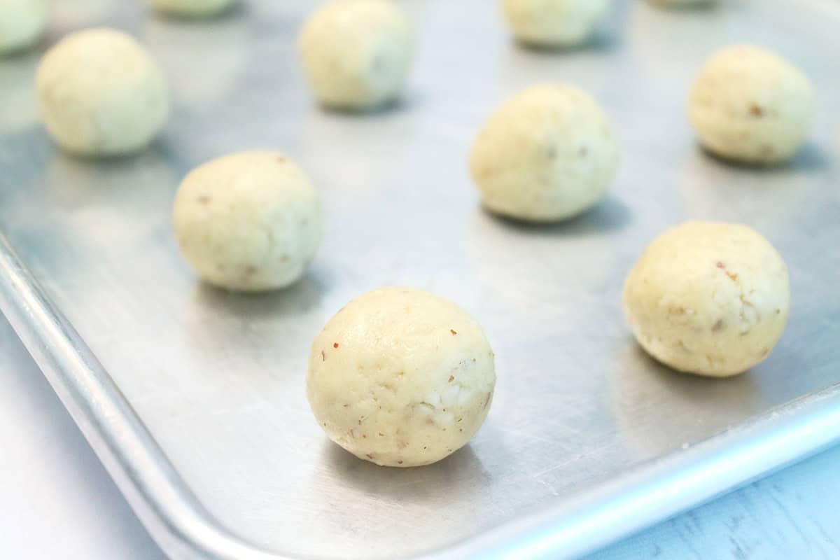 Unbaked snowball cookies on cookie sheet.