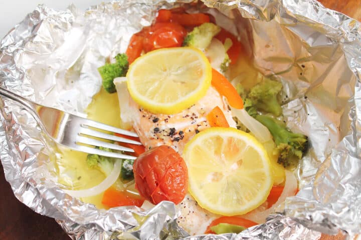 Closeup of baked salmon with foil open with fork.