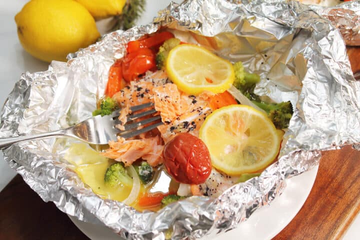 Showing flaked salmon on fork on foil packet.