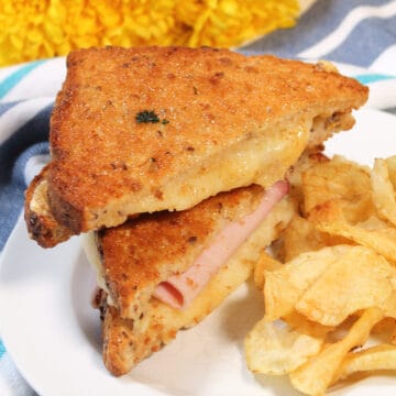 Closeup of air fried grilled cheese with chips on white plate.