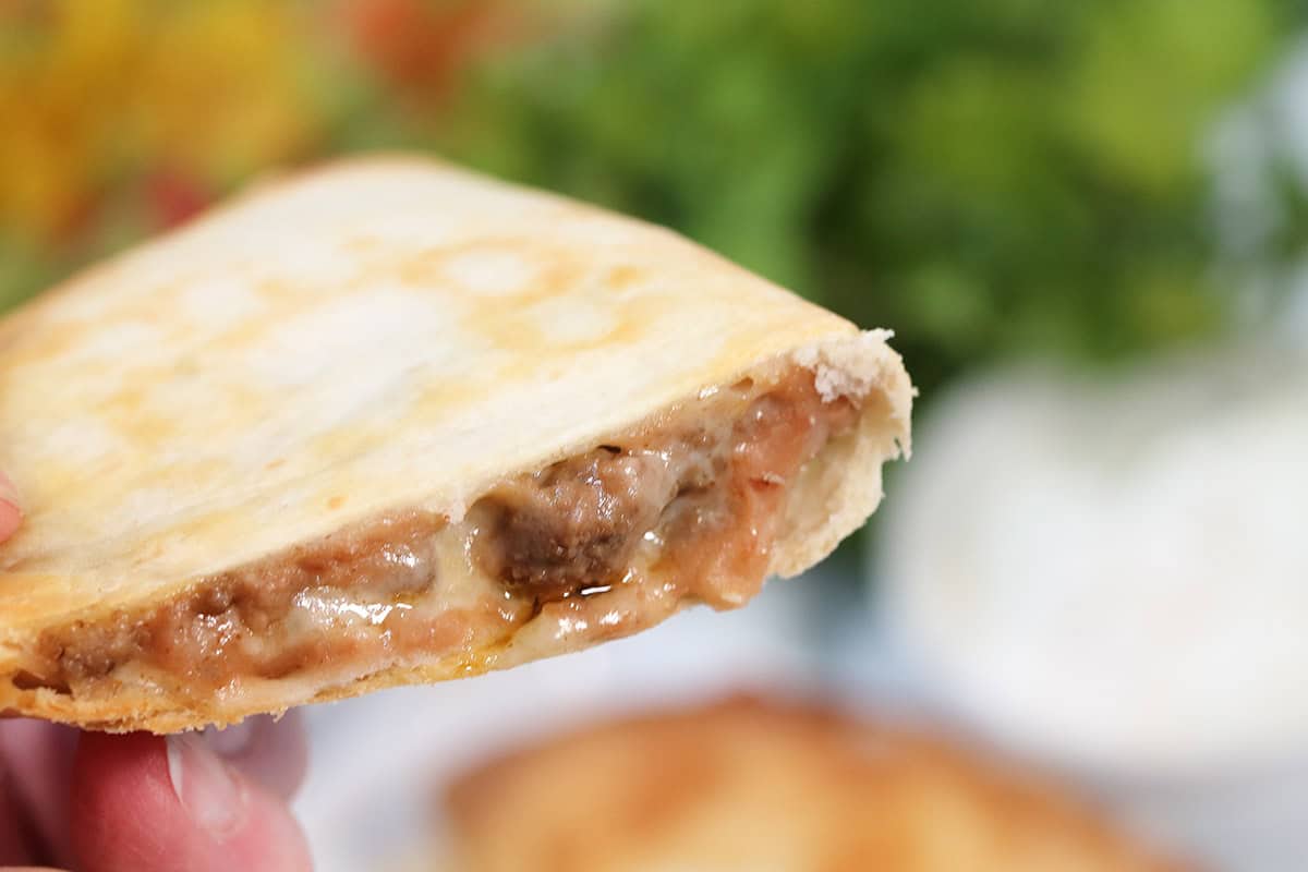 Holding beef quesadilla showing melty cheese.