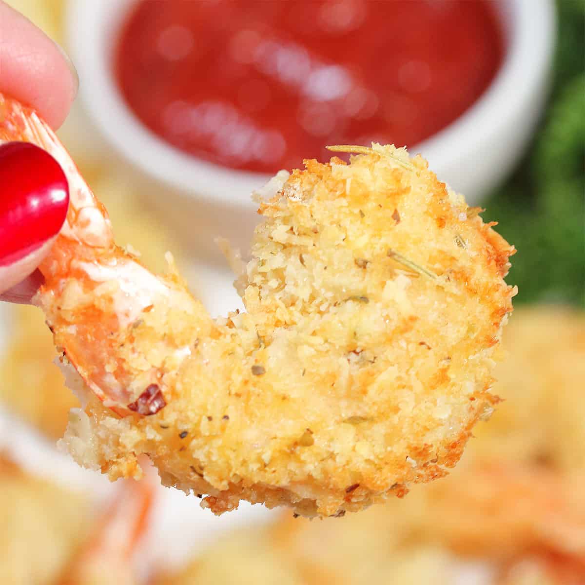 Holding a crispy air fried shrimp.