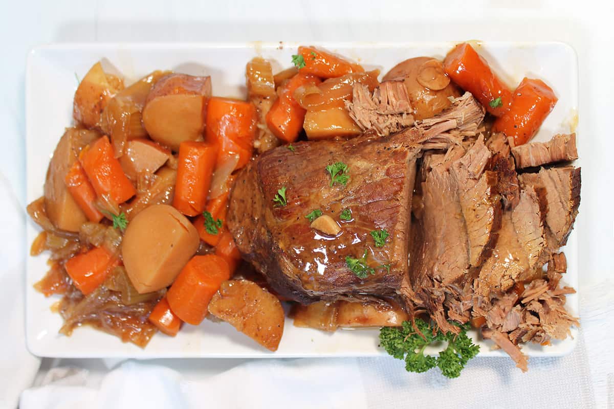 Overhead of sliced crockpot roast with potatoes and carrots.