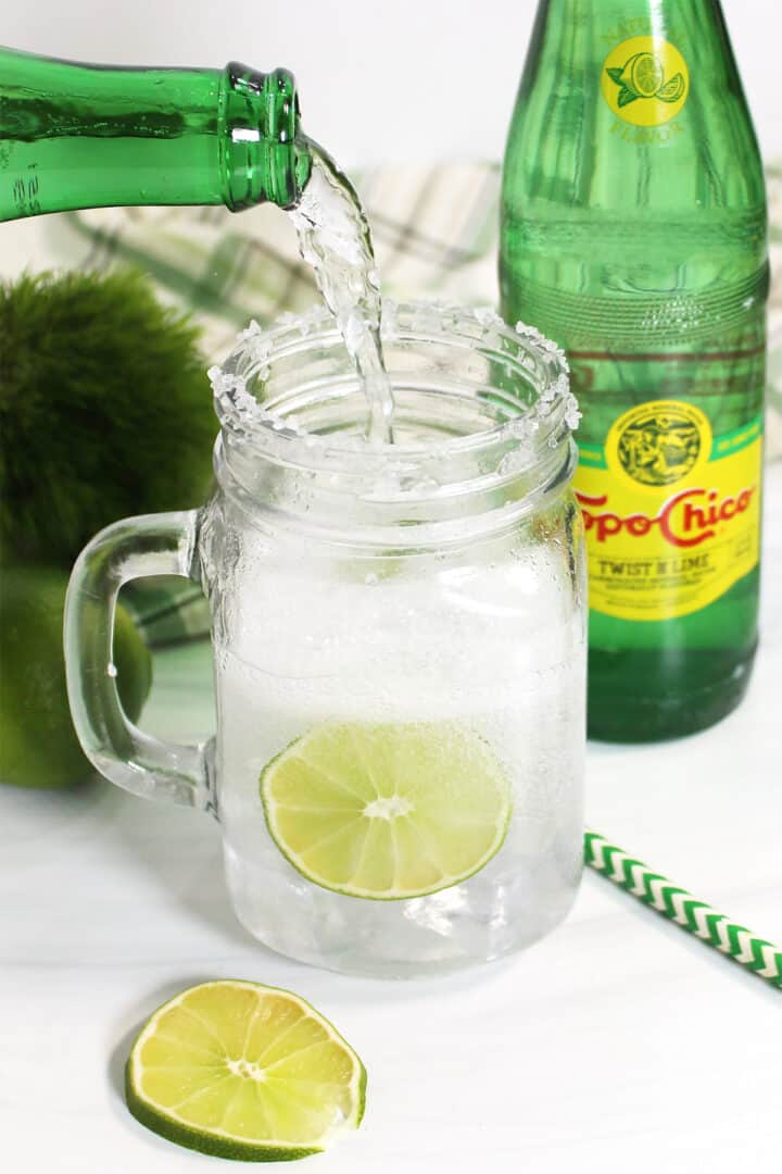 Topping off cocktail with Topo Chico Mineral Water.