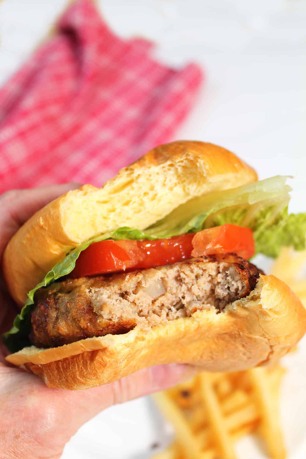 Holding burger with bite taken out.