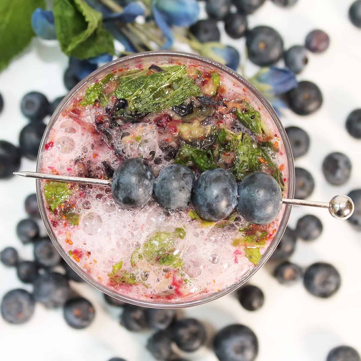 Overhead of fruity mojito amongst blueberries.