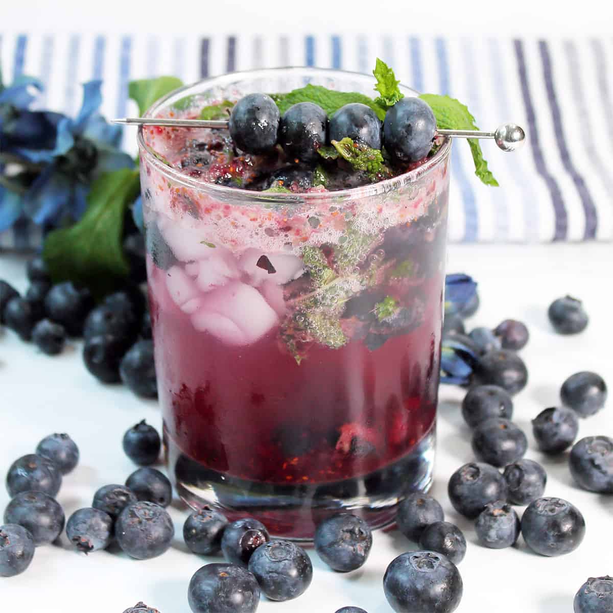 Single mojito garnished with blueberries.