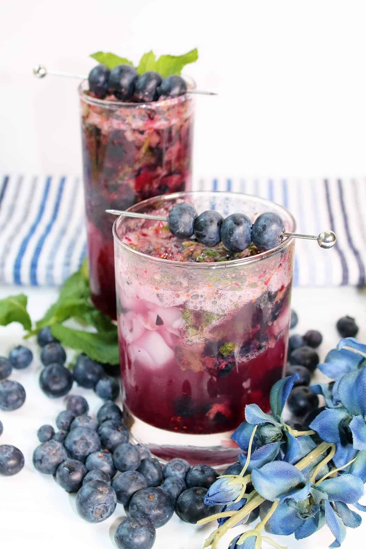 Two blueberry mojitos with blueberries and mint.