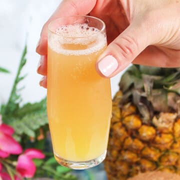 Holding tropical mimosa in champagne flute.