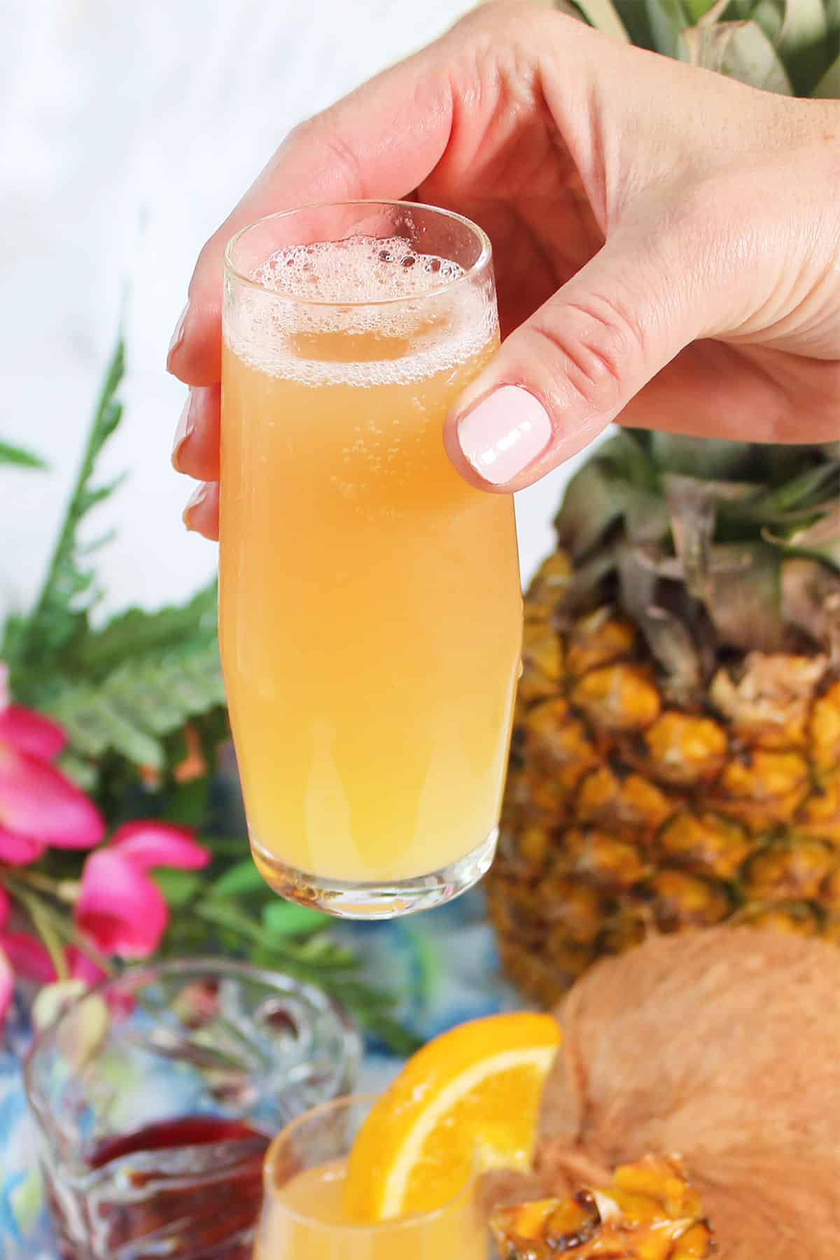 Closeup holding cranberry orange mimosa over tray.