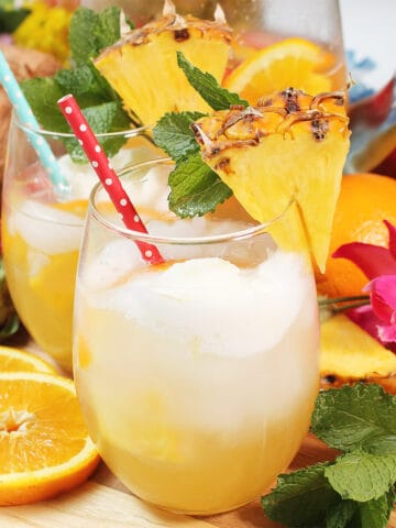 Two glasses Pineapple White wine Sangria among fruit and flowers.