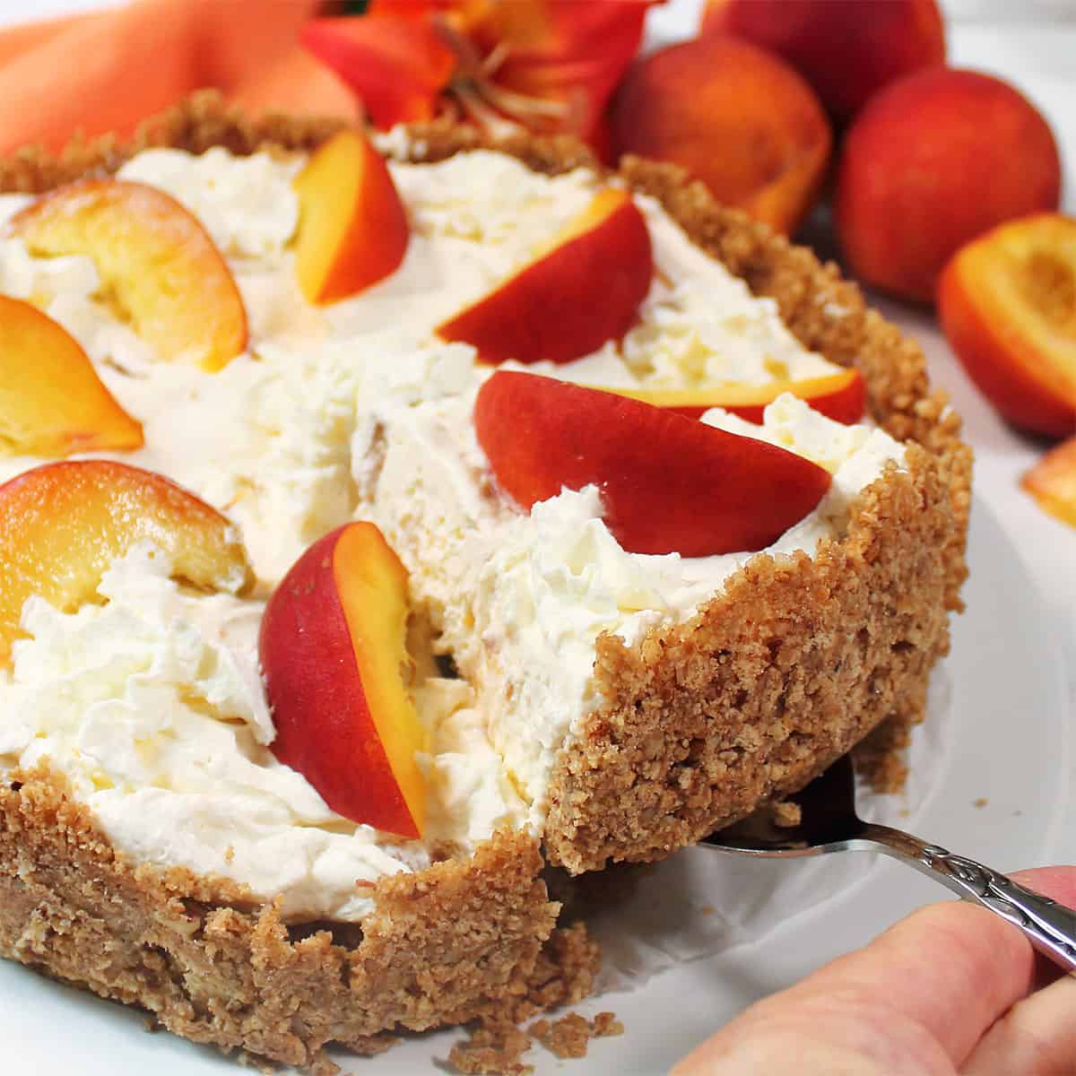 Lifting slice of no bake peach cheesecake out of pie.