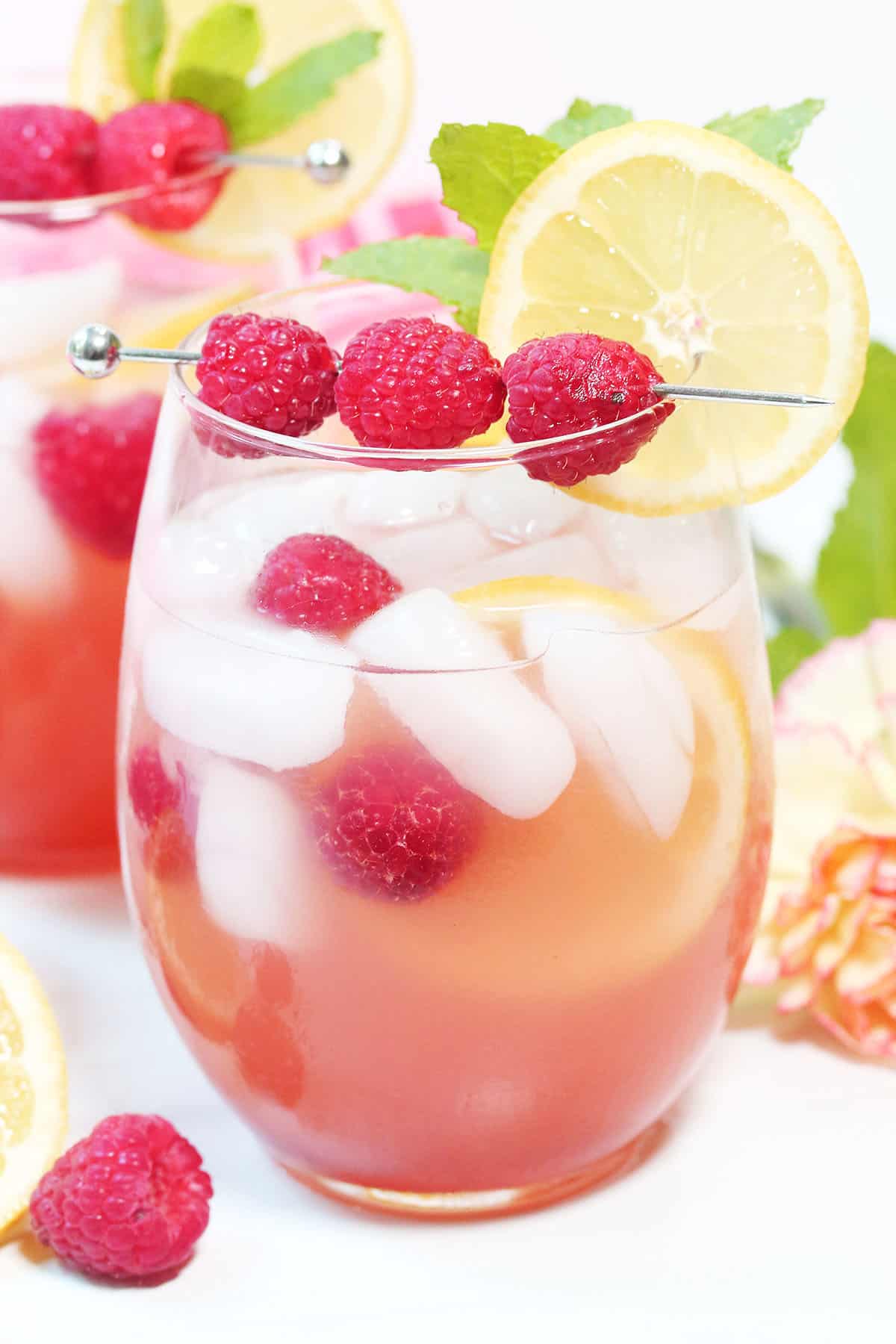 Closeup of pink lemonade cocktail with raspberries and lemon slice.