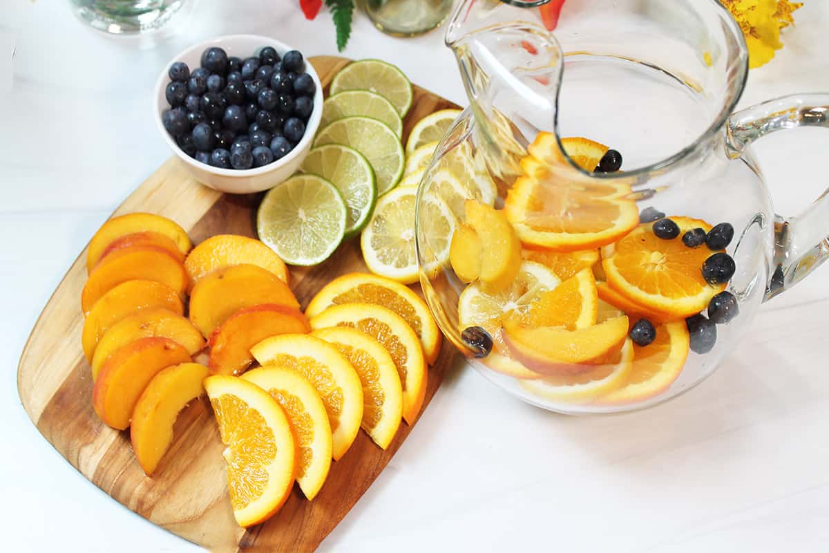 Filling pitcher with sliced fruit.