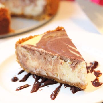 Slice of marbled cheesecake on top of chocolate drizzle.
