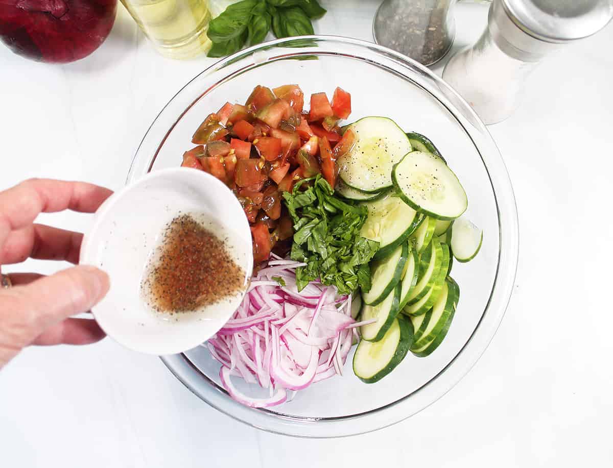 Pouring dressing over cucumber salad.